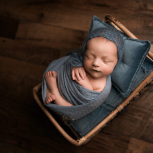 newborn photoshoot with baby boy wrapped in blue with bonnet