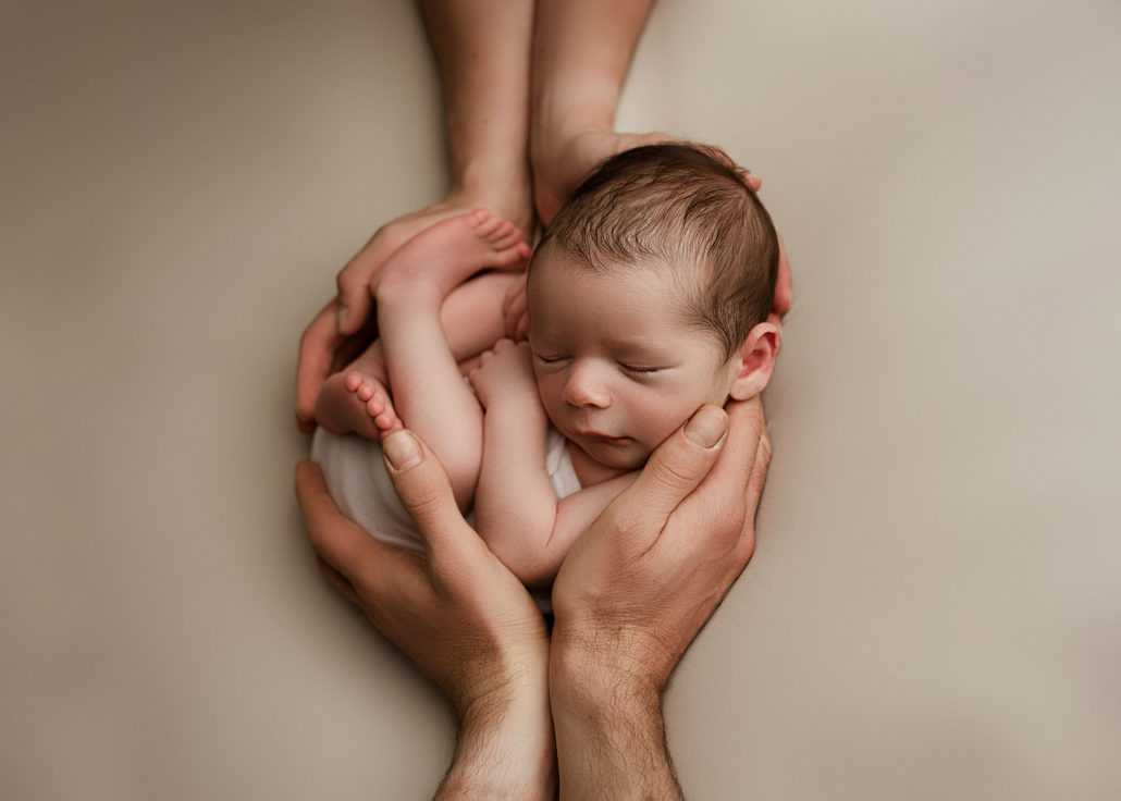 newborn in parents hands posing
