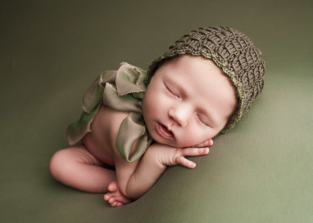 sleepy baby on green with a green bonnet Maddy Rogers Photography yorkshire
