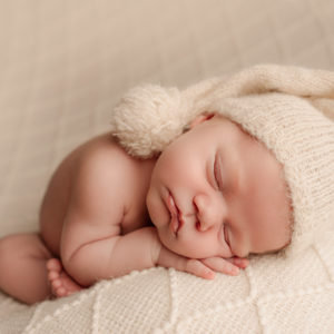 baby boy in cream hat on cream blanket