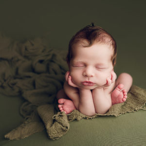 baby boy in frog pose on green fabric